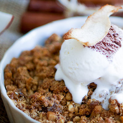 apple brown betty in a bowl with ice cream on top
