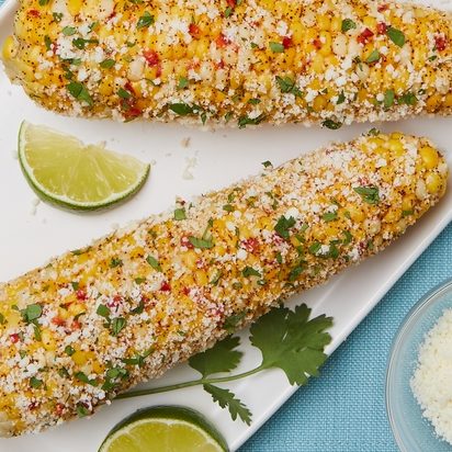 Grilled corn on a plate with limes