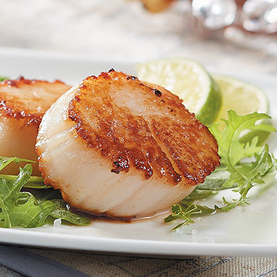 seared scallops with mixed greens in a plate
