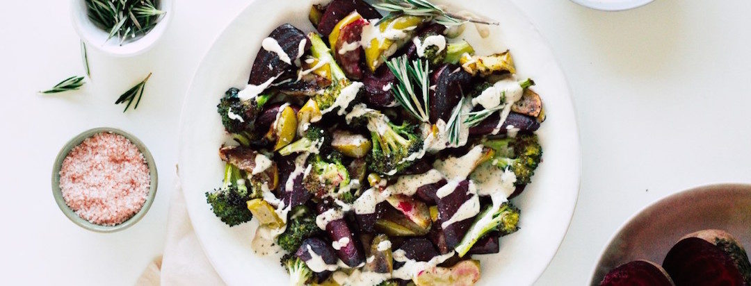 roasted apples, beets and broccoli with herb tahini sauce on a plate