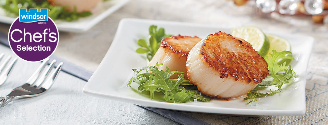 seared scallops with mixed greens in a plate