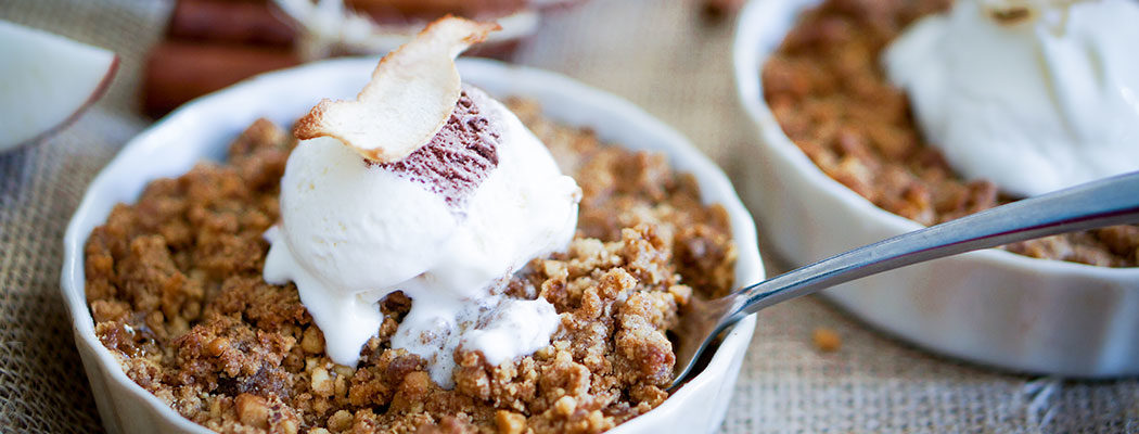 apple brown betty in a bowl with ice cream on top