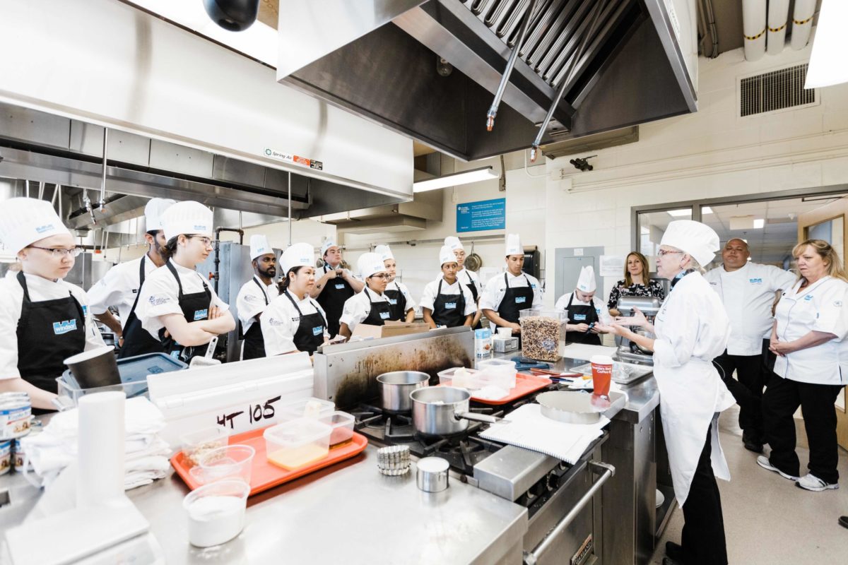 A group of culinary students in a professional kitchen setting